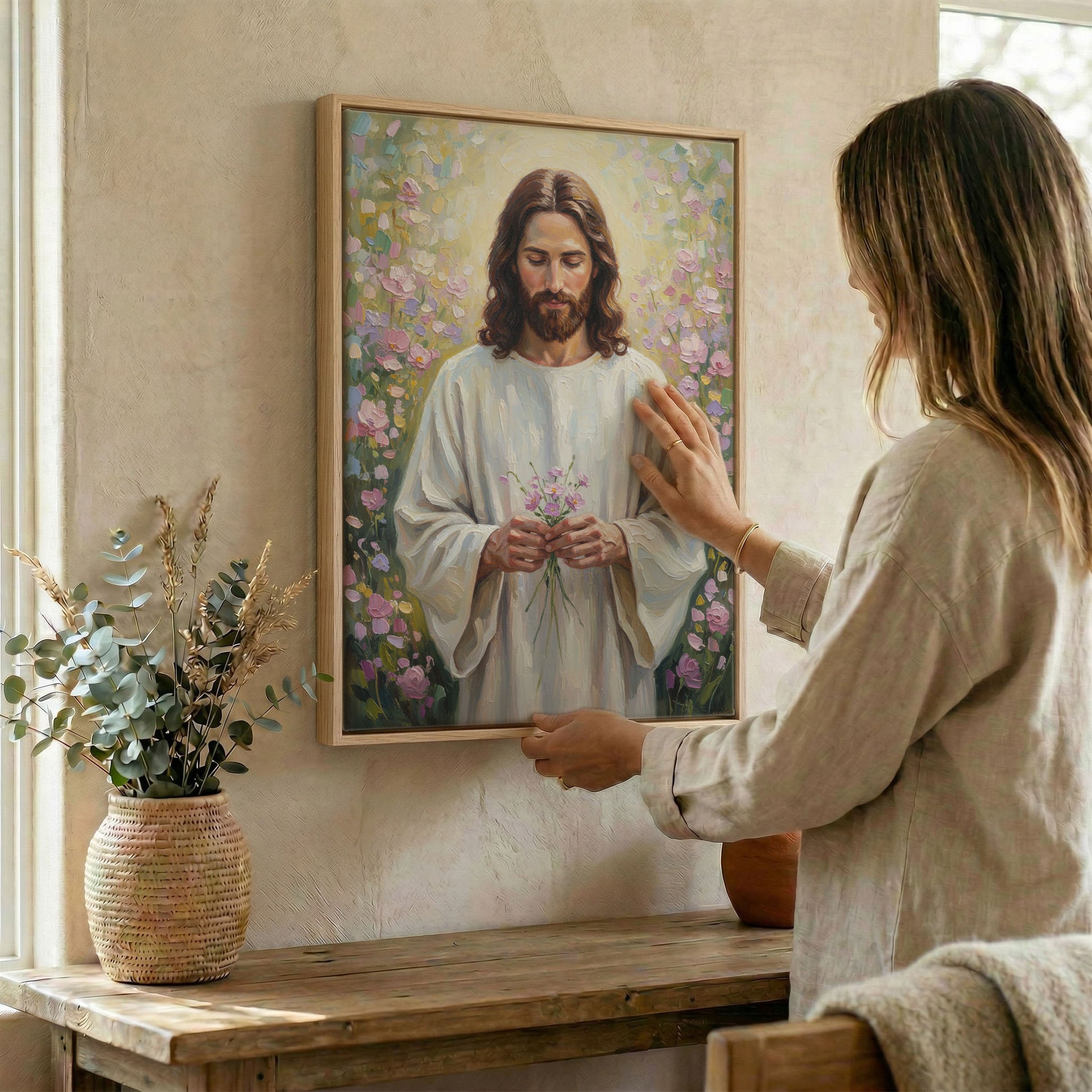 Woman hanging Jesus garden wall art in wood frame beside dried botanical arrangement