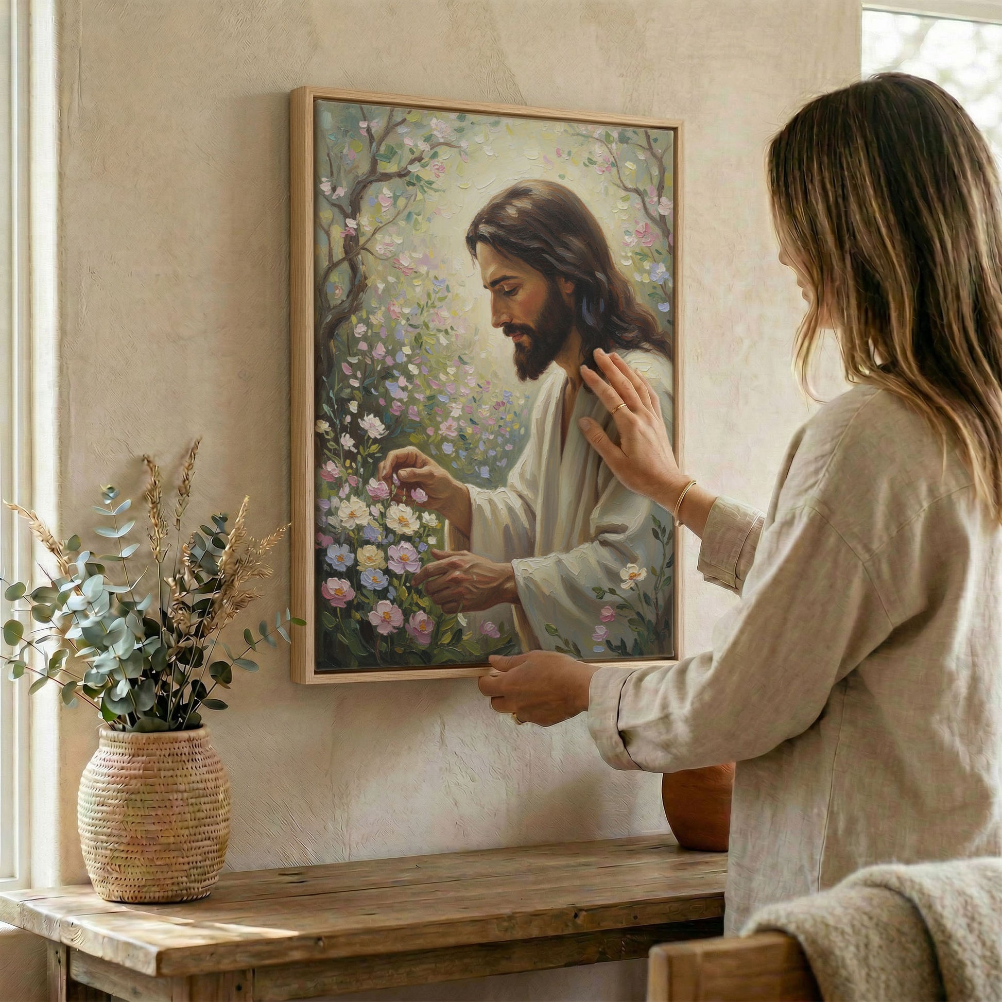 Woman hanging framed Jesus tending garden canvas print on textured wall above wooden console table
