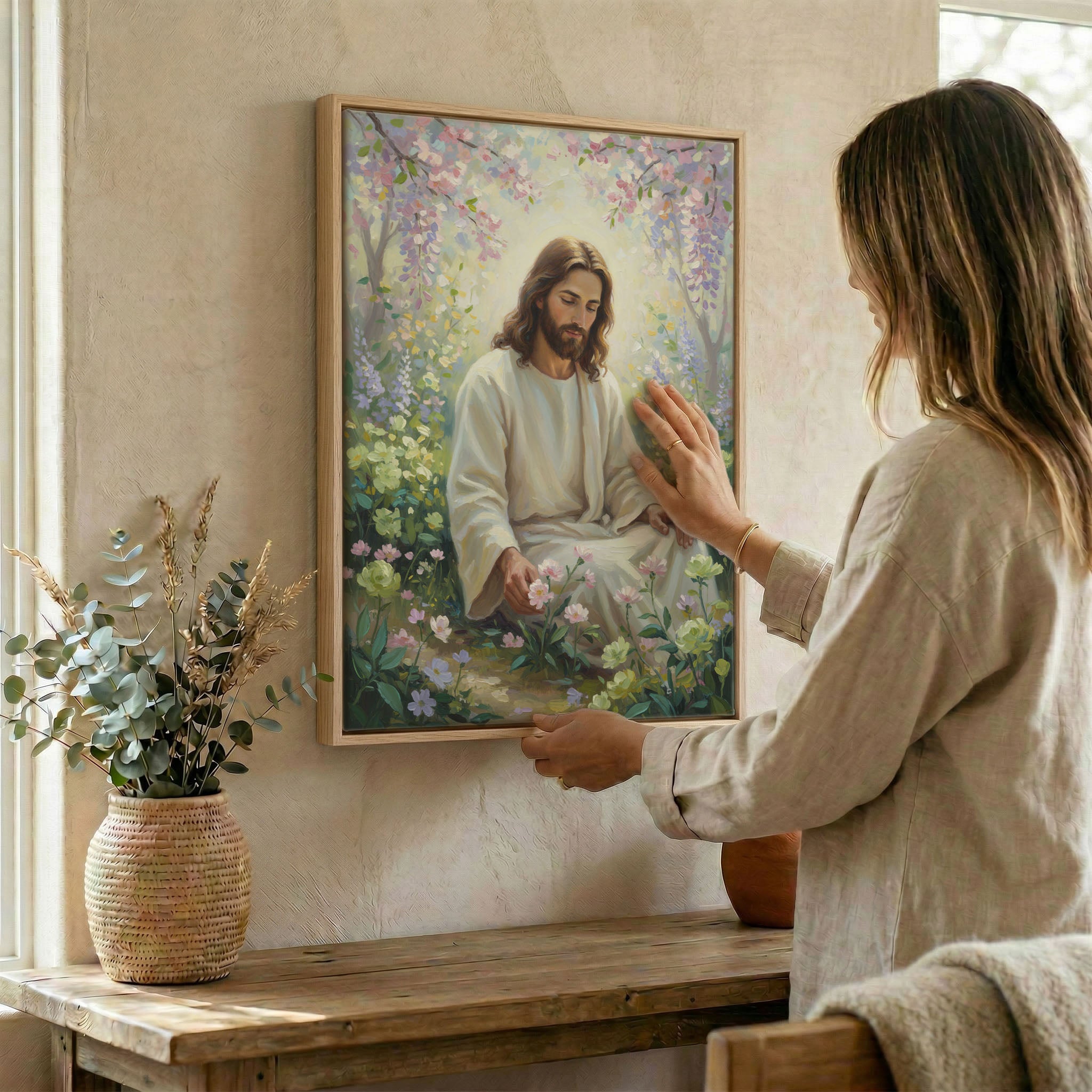 Woman hanging Jesus spring garden wall art in wood frame beside dried botanical arrangement