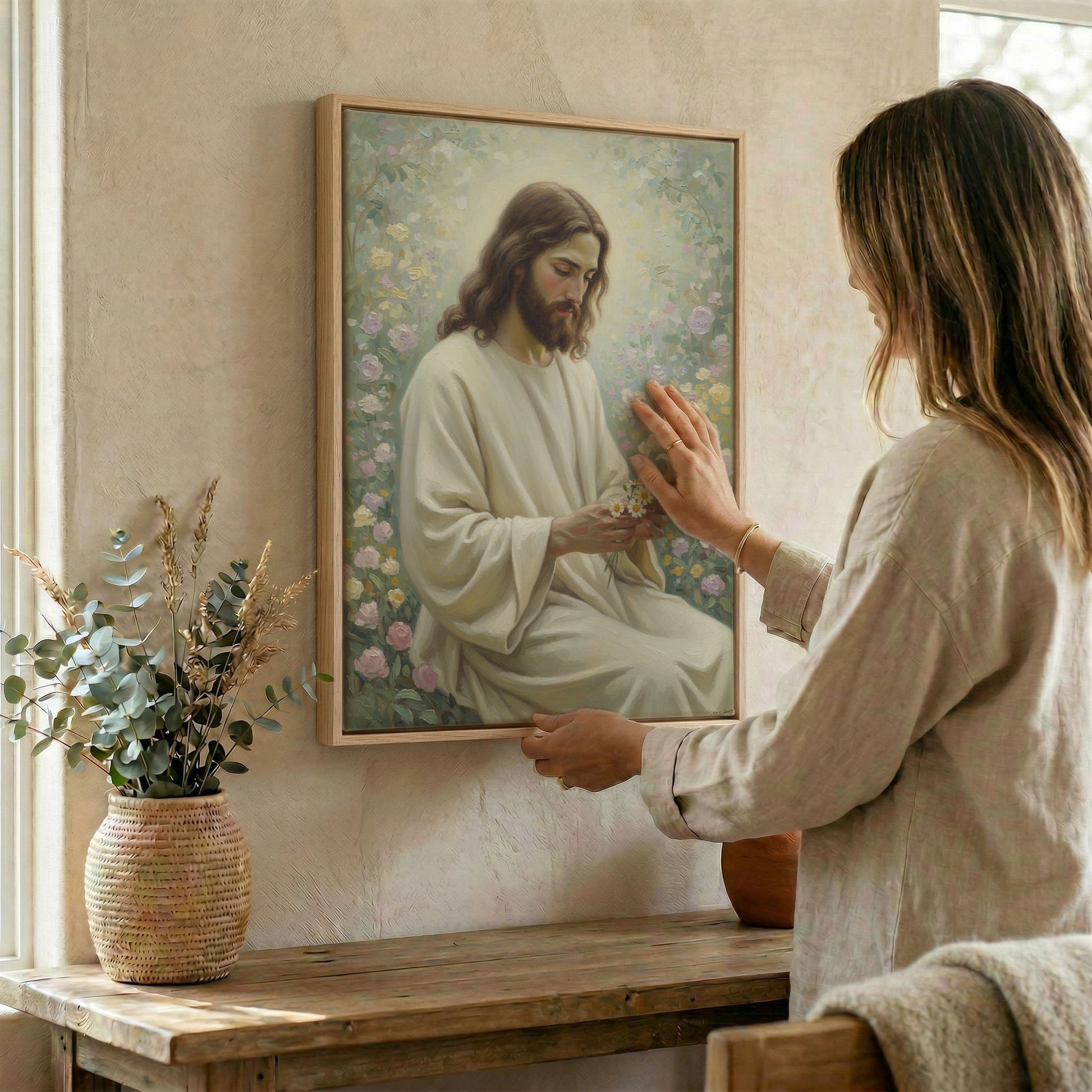Woman hanging Jesus rose garden wall art in wood frame beside dried botanical arrangement