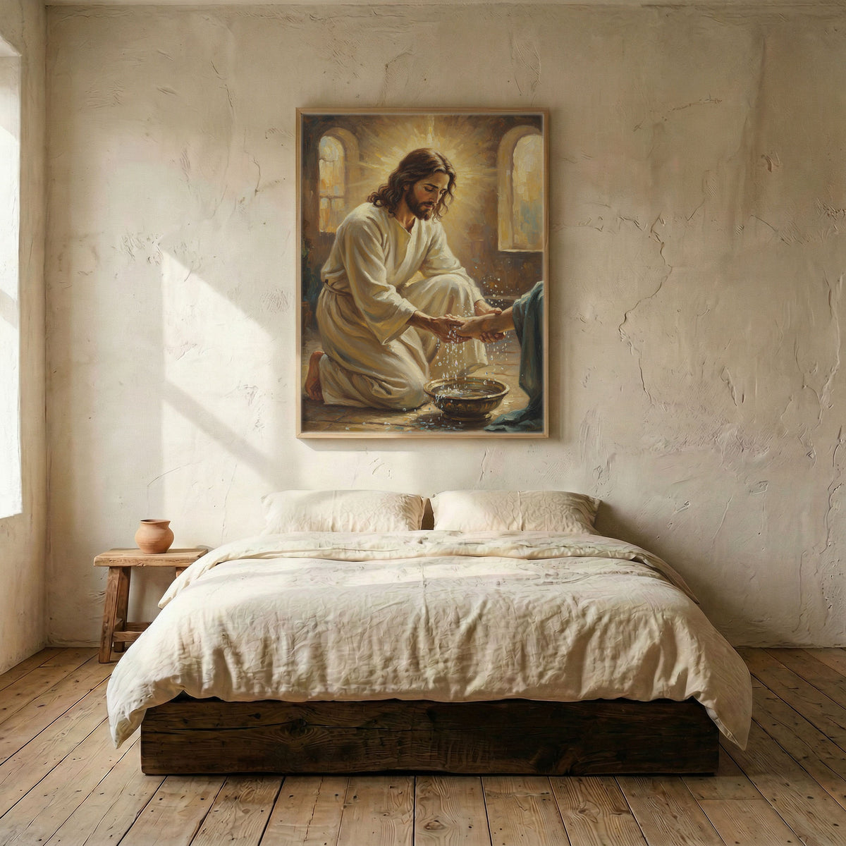 Jesus washing feet canvas in wood frame mounted above linen platform bed in serene neutral bedroom