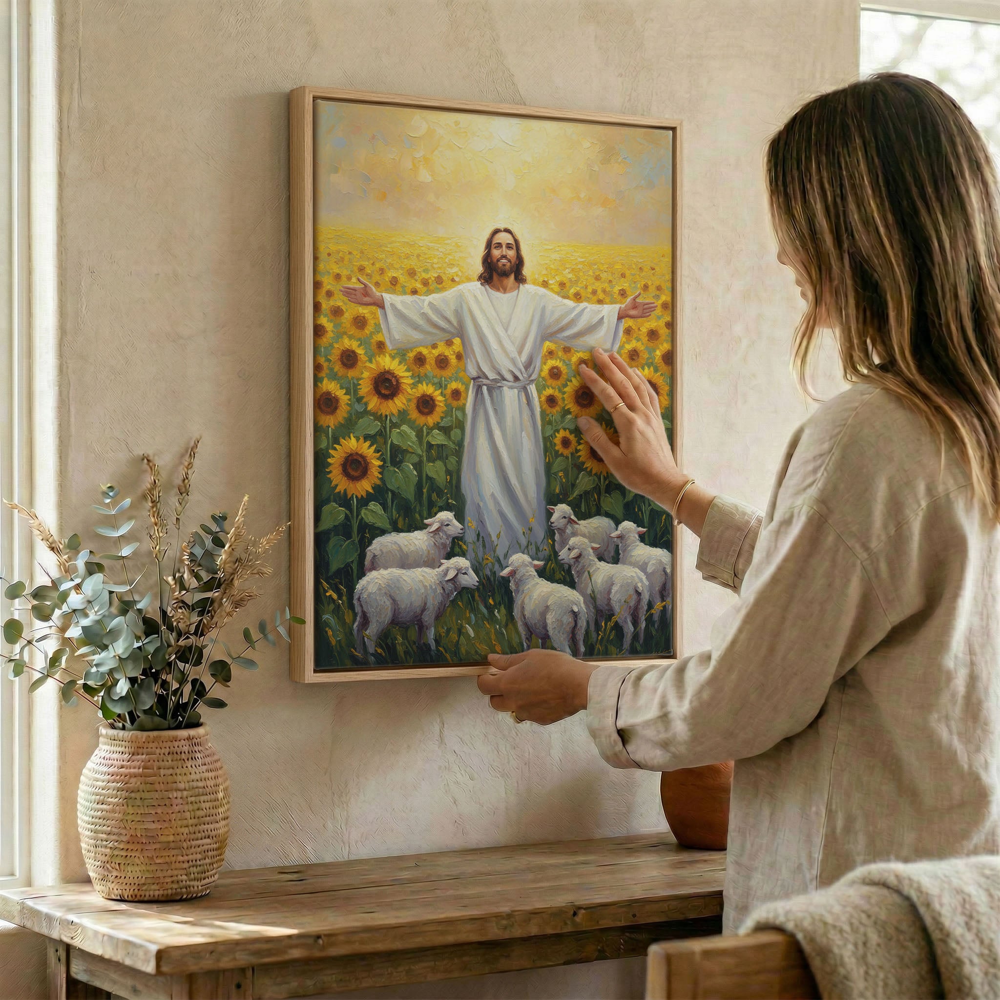 Woman hanging Jesus sunflower field wall art in wood frame beside dried botanical arrangement