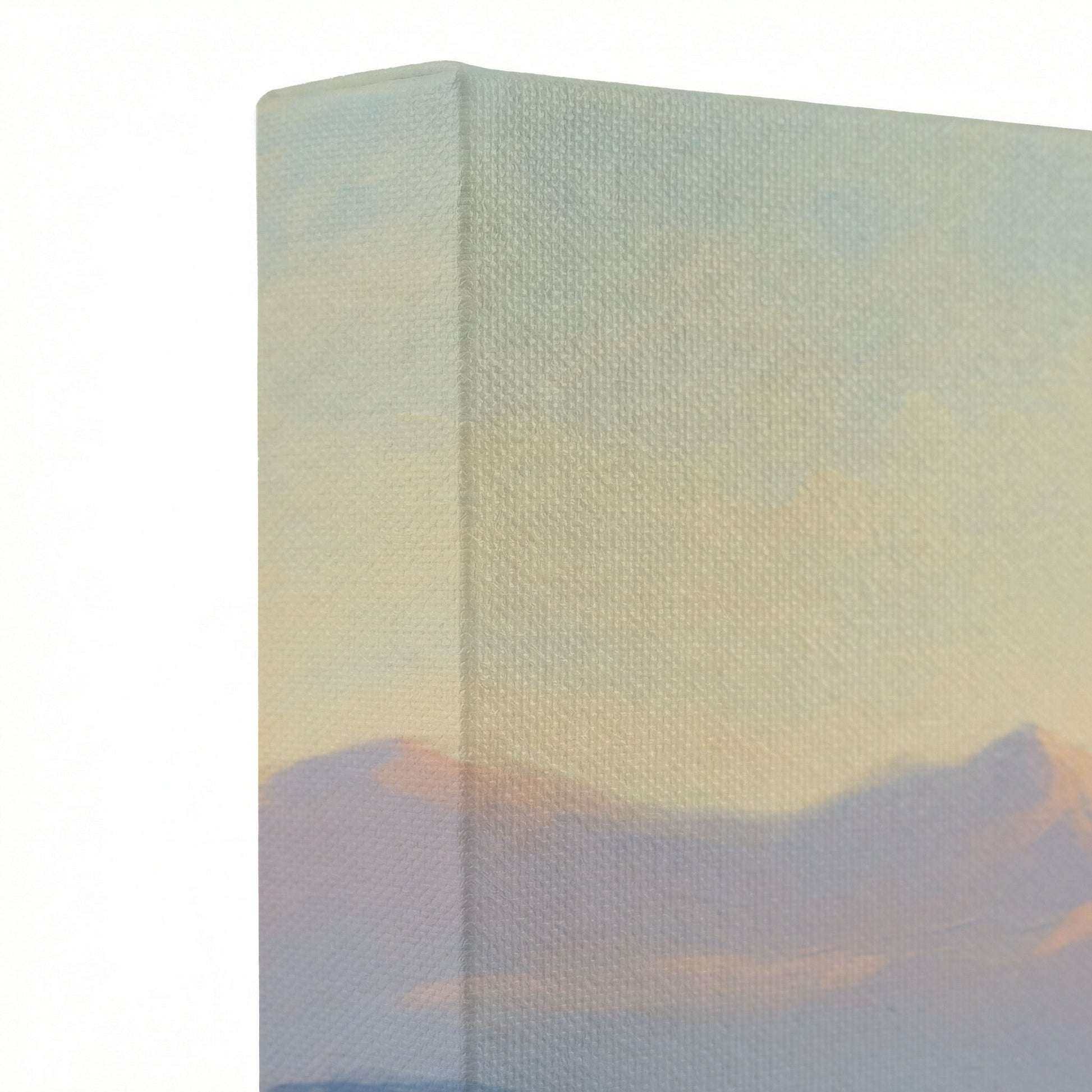 Close-up of gallery-wrapped canvas corner showing soft peach and lavender mountain sunrise sky texture on wrapped edge