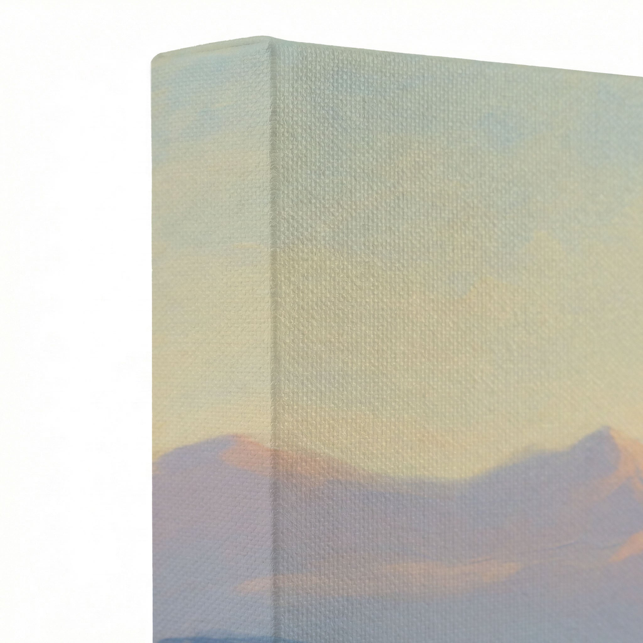 Close-up of gallery-wrapped canvas corner showing soft peach and lavender mountain sunrise sky texture on wrapped edge