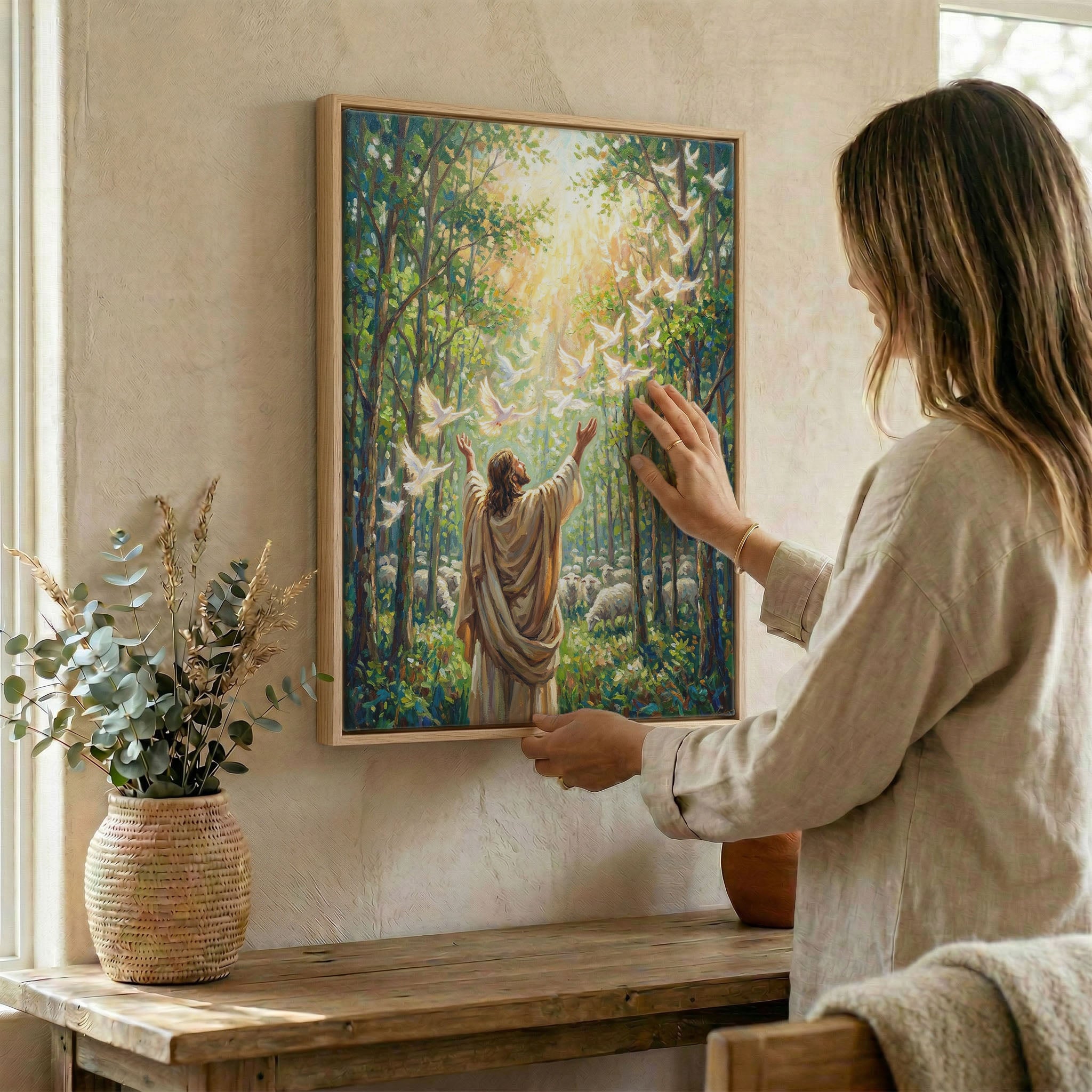 Woman placing Jesus releasing doves Holy Spirit wall art in wood frame on wall beside dried botanical arrangement